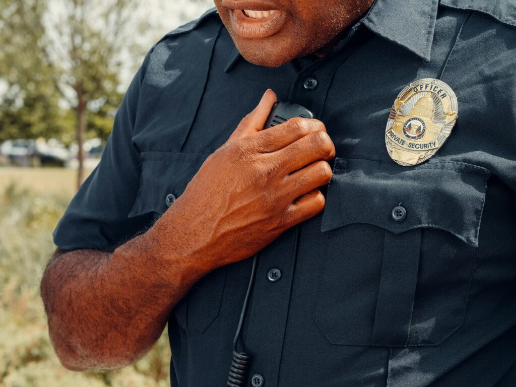 Close-up of a security officer using a radio outdoors, showcasing professional security attire.